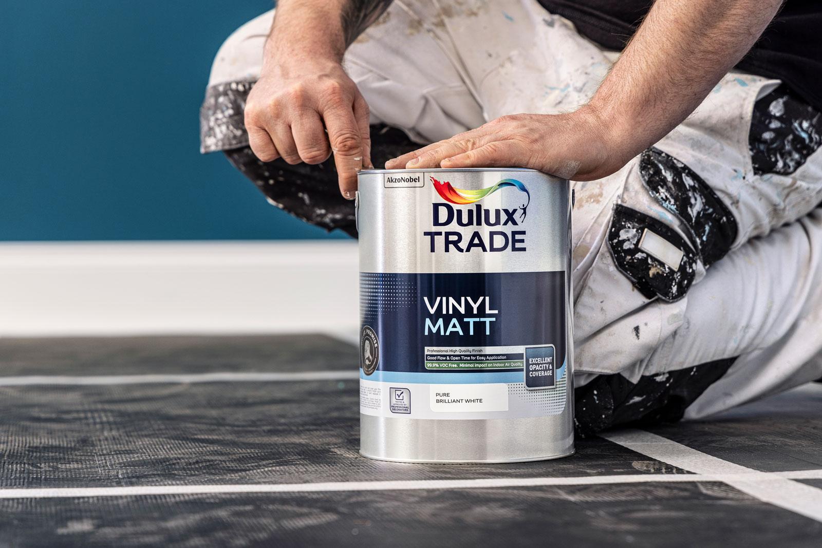 Painter opening a can of Dulux paint