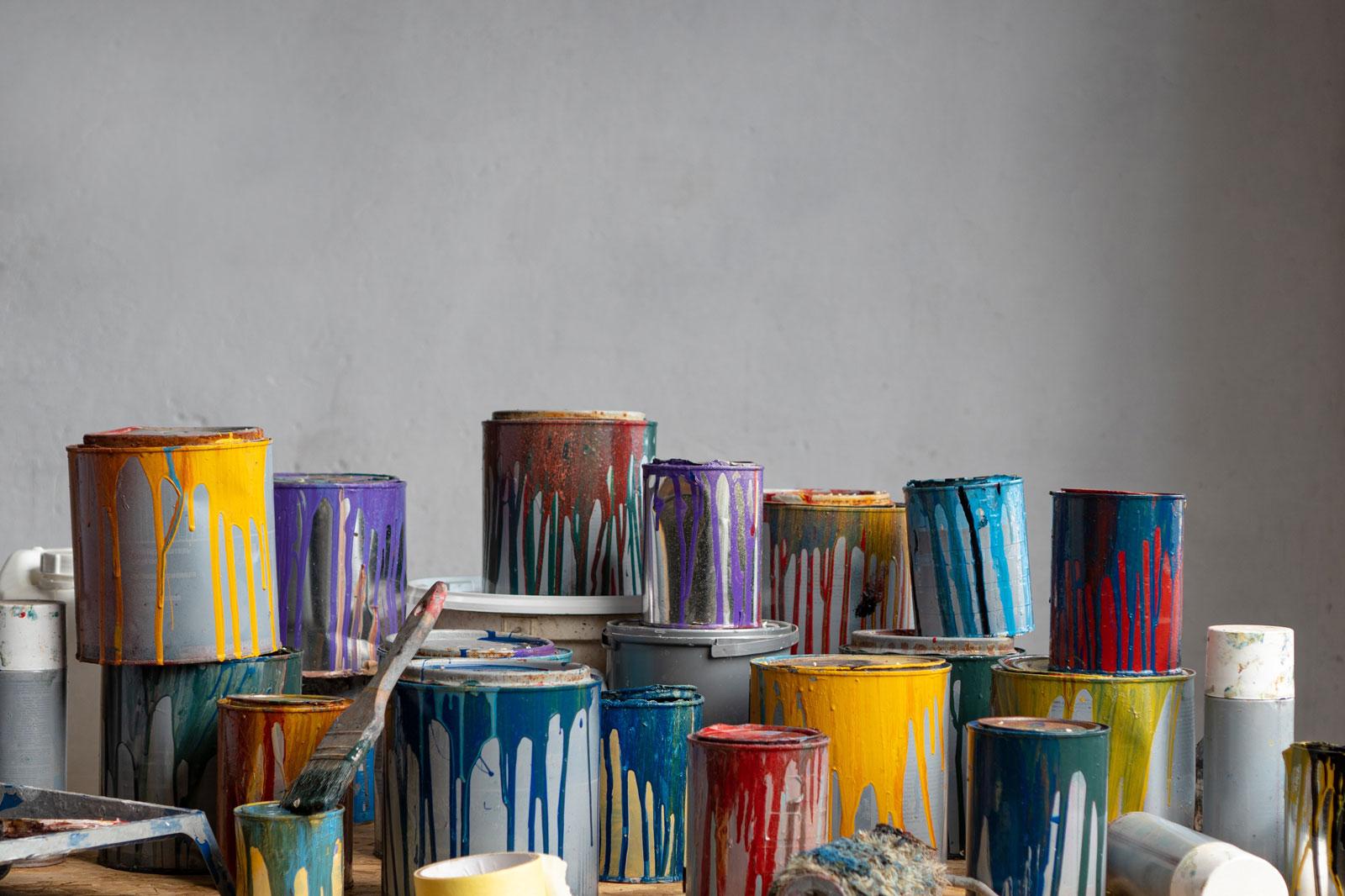 Used cans of paint stacked in a pile