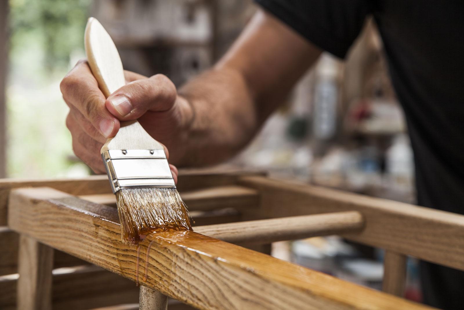 Photograph of a person varnishing wooden furniture.