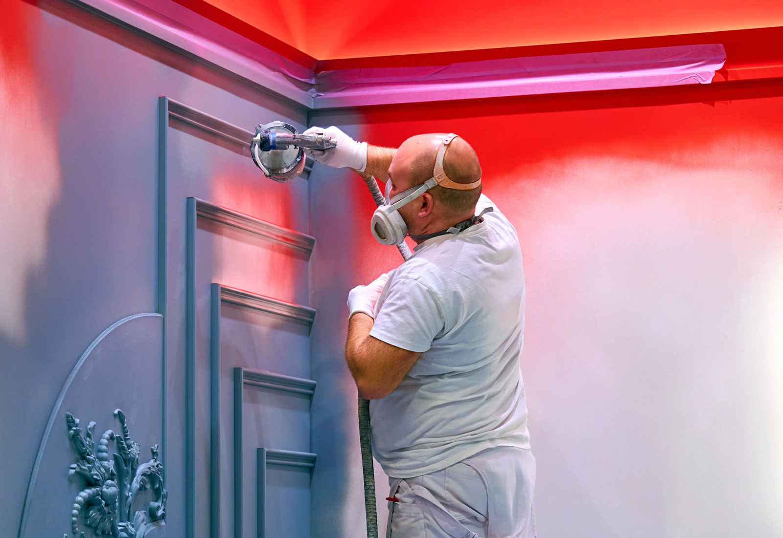Photograph of a painter up a ladder spraying a wall.