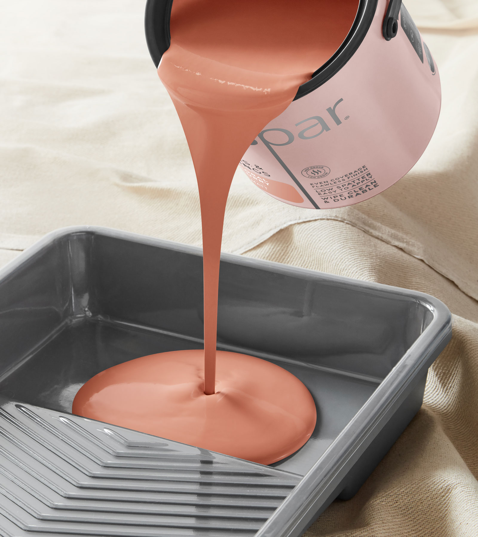 Photograph of a can of paint being poured into a roller tray