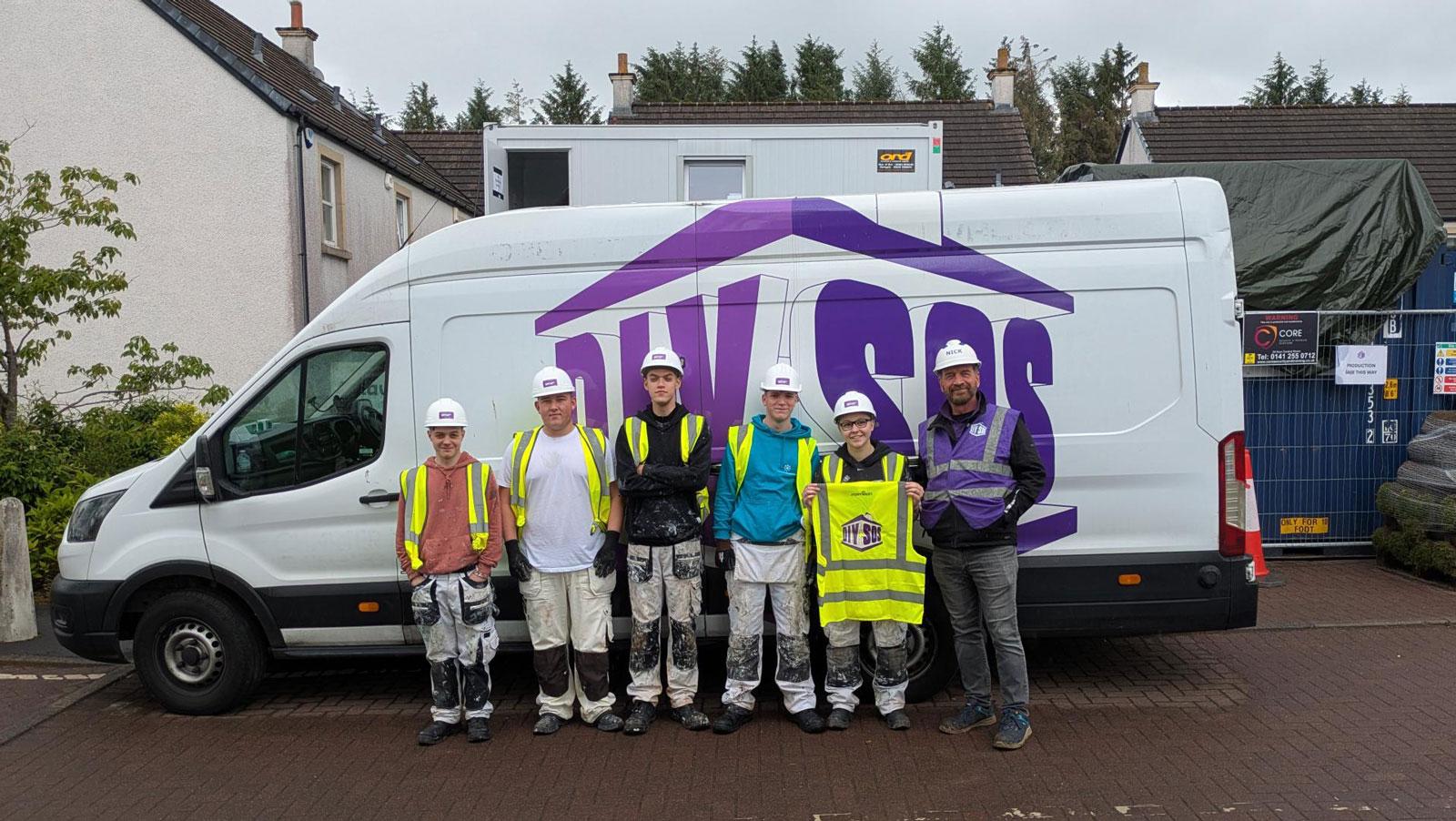 Photograph of painting and decorating apprentices from City of Glasgow College helping on the DIY SOS TV show. Presenter Nick Knowles is in purple hi-viz jacket on right-hand side.